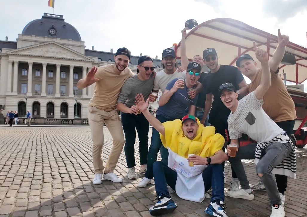 Stag party group celebrating in front of the Royal Palace of Brussels next to the beer bike